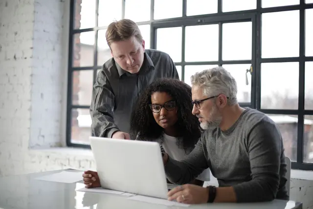 A startup team collaborating on a laptop in a bright workspace